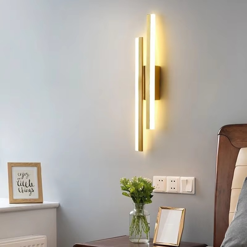Gold Lumina Linear LED wall sconce mounted above a bedside table in a bedroom