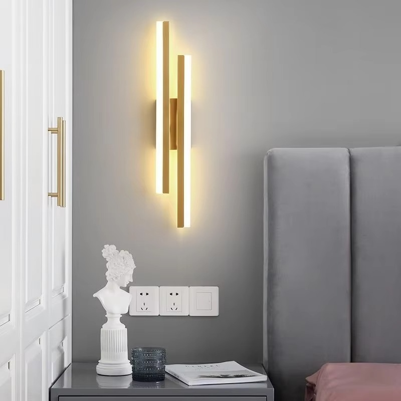 Gold Lumina Linear LED wall sconce beside a bed in a modern bedroom